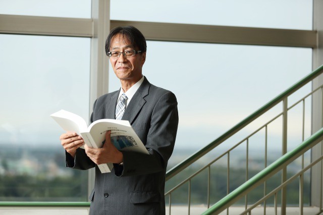 医学教育センター長の岡崎仁昭教授。手にしているのは、870ページに上るオリジナルの国家試験対策本