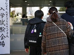 入試会場の私立中学校に入る保護者と受験生